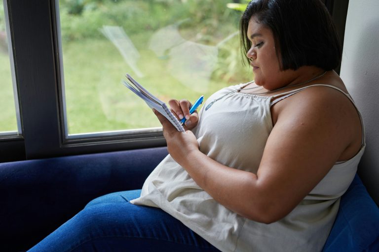 A woman on a train is writing something.